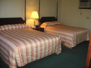 a hotel room with two beds and a lamp at Lockport Inn and Suites in Lockport