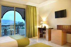 a bedroom with a bed and a desk and a balcony at Menzeh Zalagh City Center in Fez
