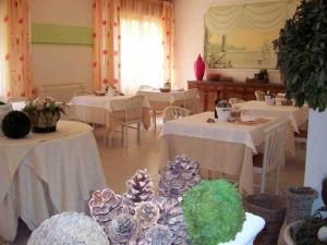 ein Zimmer mit Tischen, weißen Tischdecken und Tischlern in der Unterkunft Hotel Mirella in Castiglione della Pescaia