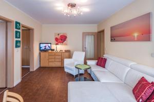 a living room with a white couch and a tv at Am Weststrand Apartmenthaus Bellamare in Kühlungsborn