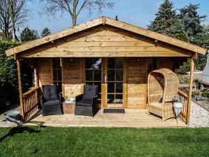 a wooden gazebo with two chairs and a table at Het parkhuisje in Zwaanshoek