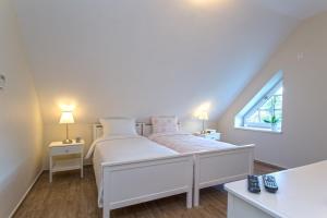 a white bedroom with a bed and a window at Green Hill Guest House in Berkovitsa