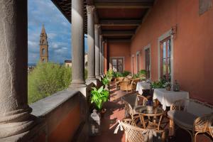 a balcony with tables and chairs and a clock tower at Hotel Palazzo Guadagni in Florence +55 photos