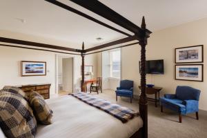 a bedroom with a bed and two blue chairs at Inch Hotel in Fort Augustus