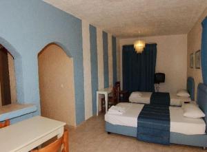 a hotel room with two beds and a table at Perla Apartments in Agia Pelagia