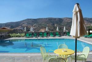 una piscina con mesa amarilla, sillas y sombrilla en Perla Apartments en Agia Pelagia
