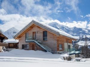 a log cabin in the snow with mountains in the background at Chalet Avista in Rosswald