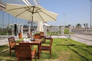 Raoum Inn Khafji Corniche في الخفجي: طاولة وكراسي مع مظلة على العشب