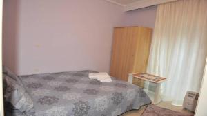 テッサロニキにあるCozy Apartmentの小さなベッドルーム(ベッド1台、木製キャビネット付)