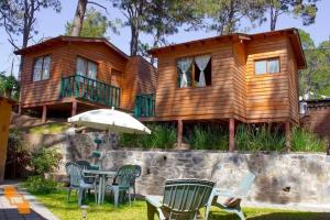 a wooden house with a table and chairs and an umbrella at Cabañas Monte Alto Hotel Boutique in Valle de Bravo