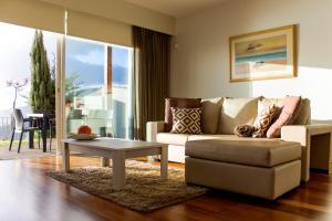 a living room with a couch and a table at Hill Houses - Savoy Signature in Arco da Calheta