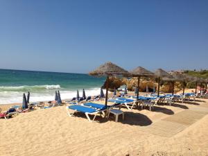 a bunch of chairs and umbrellas on a beach at Albufeira Bicos Beach Apartment in Albufeira