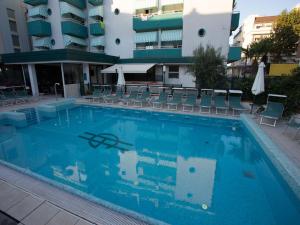 a large swimming pool with chairs and a building at Hotel Gaby in Rimini