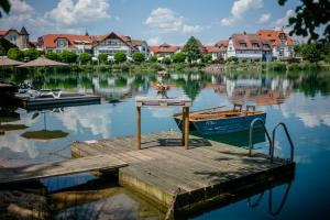 a dock with a small boat on the water at Seehotel Niedernberg - Das Dorf am See in Niedernberg