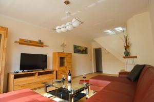 ein Wohnzimmer mit einem roten Sofa und einem Flachbild-TV in der Unterkunft Gästehaus Fährmann in Vehra
