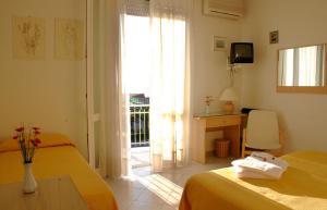 a bedroom with two beds and a desk and a window at Hotel Alk in Marina di Pietrasanta
