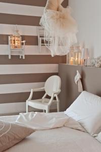 a bedroom with a striped wall with a bed and a chair at Hotel Roma in Grottammare