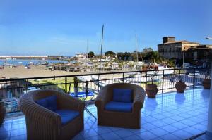 two chairs on a balcony with a view of a beach at Terrazza sul Mare in Giardini Naxos