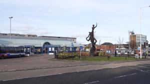 a city street with a statue next to a bus at Glenrothes Central Apartment in Glenrothes