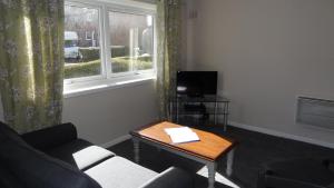 sala de estar con sofá, mesa y ventana en Glenrothes Central Apartment, en Glenrothes