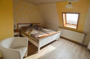 a bedroom with a bed and a chair and a window at Gästehaus Fährmann in Vehra