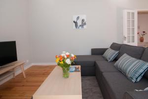 uma sala de estar com um sofá e um vaso de flores em Cosy Baixa Apartment em Lisboa