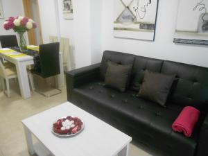 sala de estar con sofá negro y mesa en Playa Sol II Apartment, en Denia