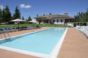 a swimming pool with chairs and a house at Agriturismo Cà Mignone in Urbino