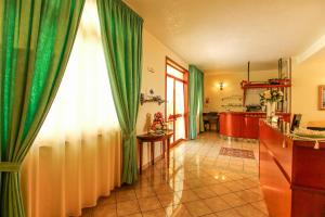 a living room with green curtains and a kitchen at Gran Residence Marisa in Lampedusa