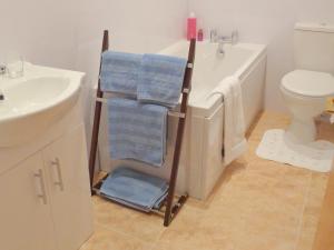 a bathroom with a towel rack next to a bath tub at Ballacowell Cottage in Sulby