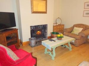 sala de estar con mesa de centro y chimenea en Ballacowell Cottage, en Sulby
