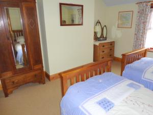 1 dormitorio con 2 camas, espejo y tocador en Ballacowell Cottage, en Sulby