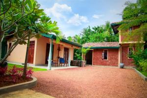 a house with a gravel driveway in front of it at Lenora Villas in Bentota