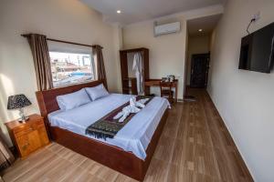 a bedroom with a bed and a window and a television at Phnom Penh Le Vincent Hotel in Phnom Penh
