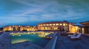 a swimming pool in front of a building at night at Dera Masuda Luxury Resort in Pushkar