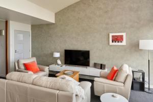 a living room with two couches and a flat screen tv at Tamar River Apartments in Rosevears