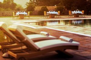 a group of tables and chairs sitting next to a pool at Dera Masuda Luxury Resort in Pushkar