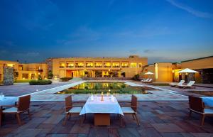 a hotel with a table and chairs and a pool at Dera Masuda Luxury Resort in Pushkar