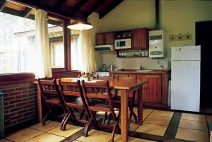 a kitchen with a wooden table and a white refrigerator at Cabañas El Ocio in Mar de las Pampas