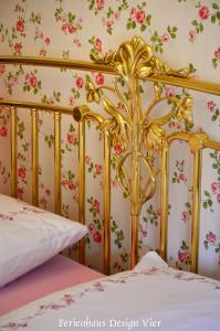 a bedroom with a gold bed with flowers on the wall at Lehmgefühl, Design Vier, La Petite Maison in Trier