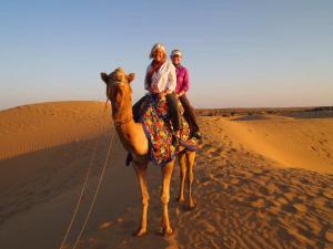 two people riding on a camel in the desert at Dera Masuda Luxury Resort in Pushkar