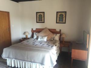 a bedroom with a large bed with two lamps and two tables at Lairds Lodge in Underberg