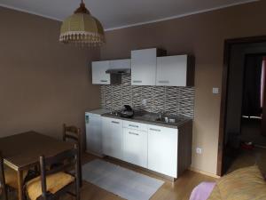 a kitchen with white cabinets and a table in a room at Guest House Raukar in Crni Lug