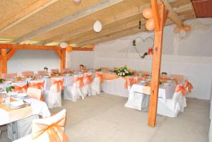AbaújszántóにあるSátor-Hegy Vendégházの白いテーブルとオレンジの弓が並ぶ宴会場