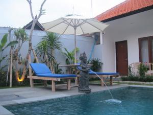 a fountain with an umbrella and a table and chairs at Temuku Guest House in Canggu