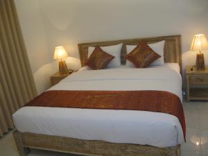 a bedroom with a large bed with two lamps at Temuku Guest House in Canggu