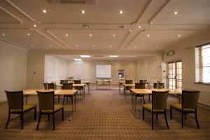 a conference room with tables and chairs and a whiteboard at Cotswold Lodge Hotel in Oxford