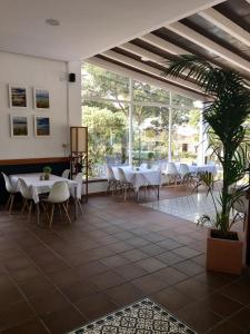 a restaurant with white tables and chairs and a plant at Hotel Marisma Sancti Petri in Chiclana de la Frontera