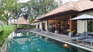 a resort with a swimming pool and a house at Rouge - Private Villa Condense in Ubud