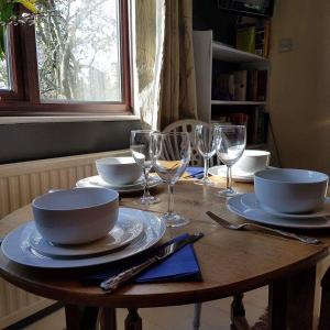 una mesa de madera con platos y copas de vino. en Dilkara Apartment Glastonbury en Glastonbury